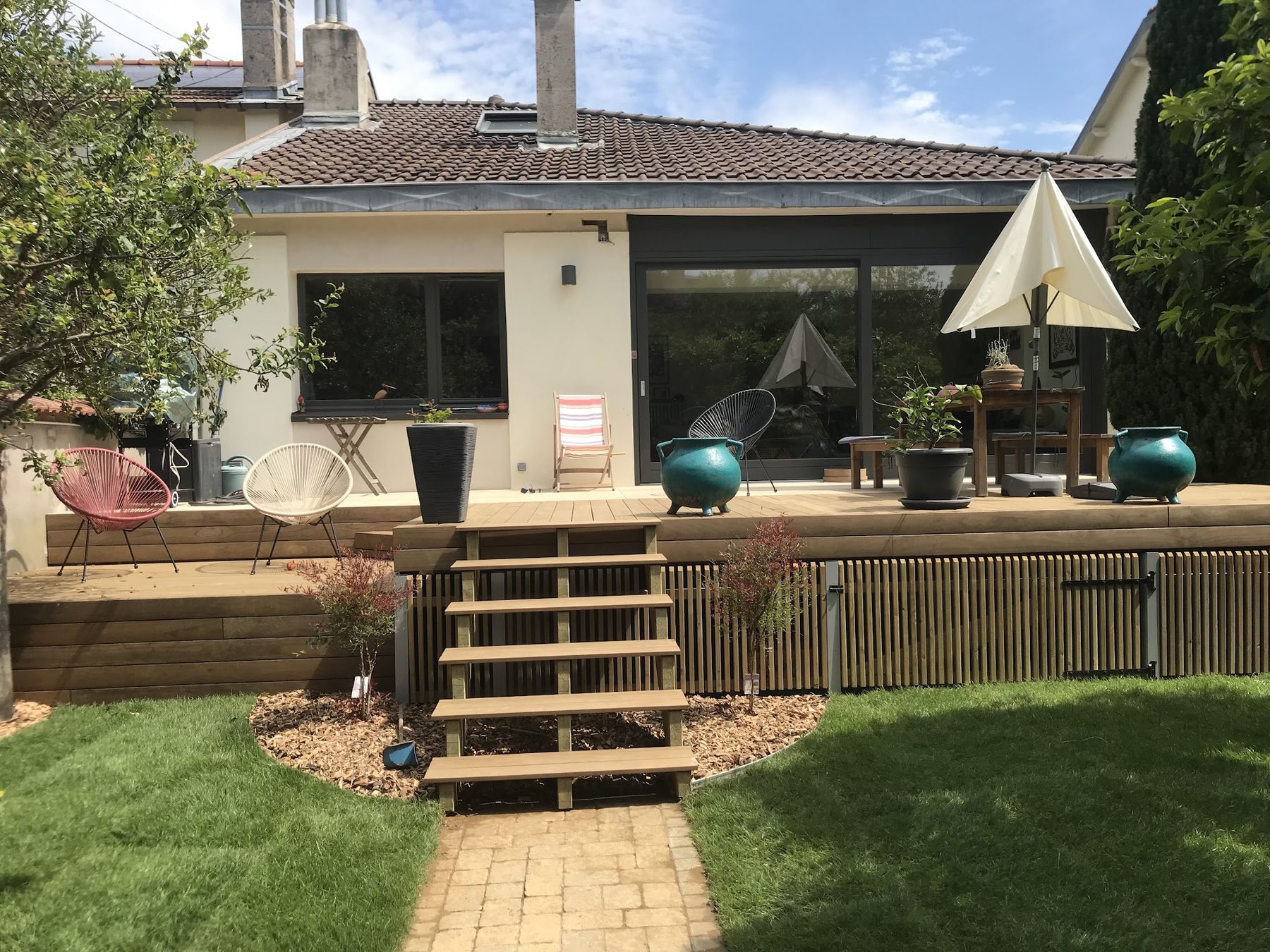 Grande terrasse en bois surélevée avec escalier vers le jardin